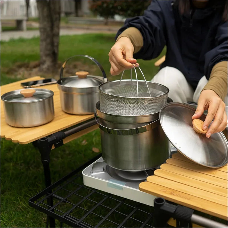 Tragbarer campingkocher mit metallkochgeschirr.