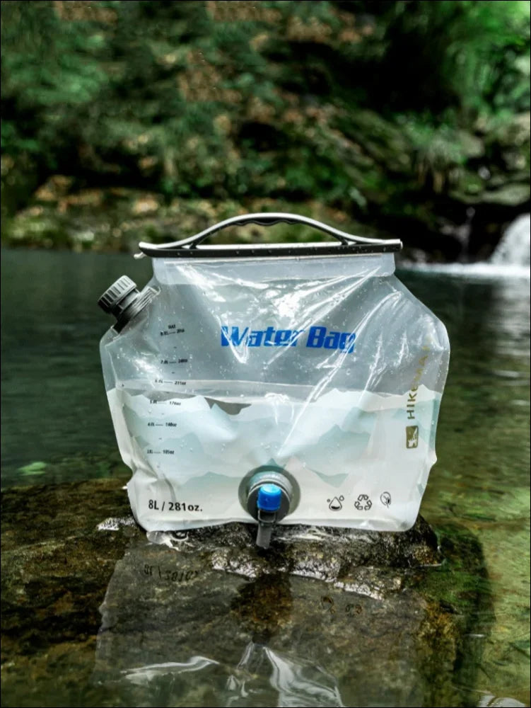 Zusammenklappbarer wasserbehälter mit der aufschrift ’water bag’, der auf einem felsen in einem bach steht.