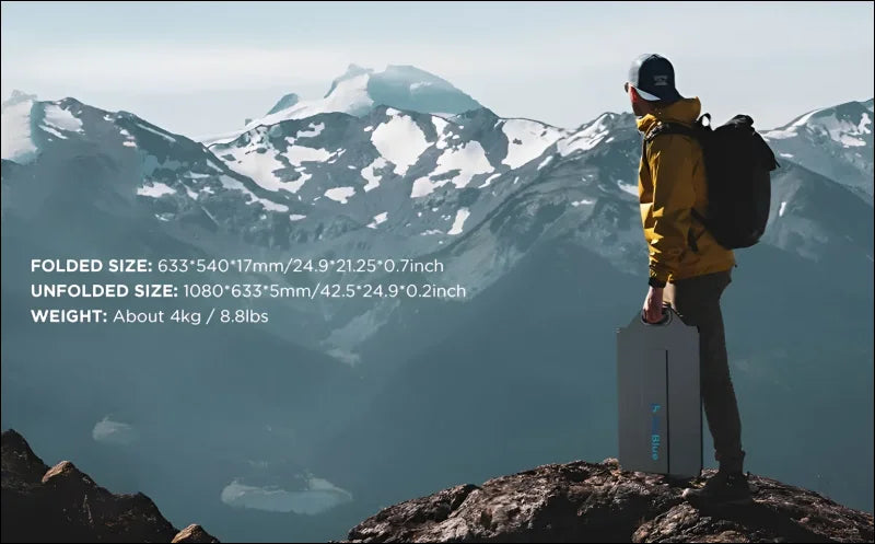 Wanderer mit gelber jacke und rucksack steht auf einem felsvorsprung mit blick auf schneebedeckte berge.