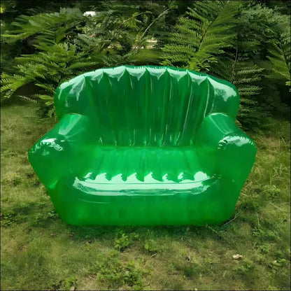 Ein grüner plastikstuhl im gras neben einem aufblasbaren outdoor sofa