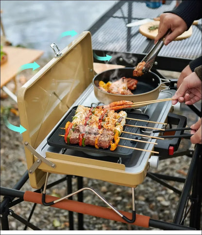 Tragbarer campingkocher mit grill und bratpfanne für spieße und andere speisen.