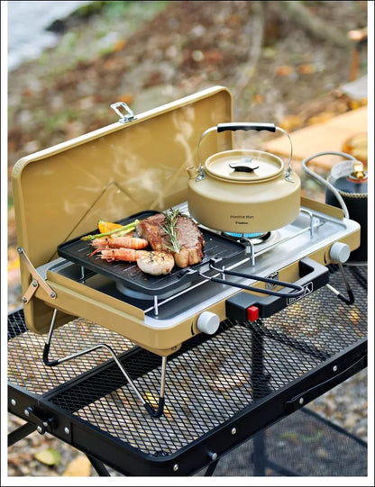 Tragbarer campingkocher mit grillplatte und kessel zum kochen von speisen im freien.