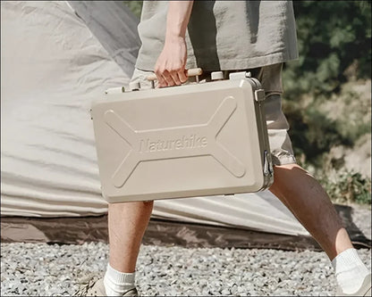 Beigefarbene hartschalen-aktentasche mit dem schriftzug ’naturehike’, die von einer person in der freien natur getragen wird.