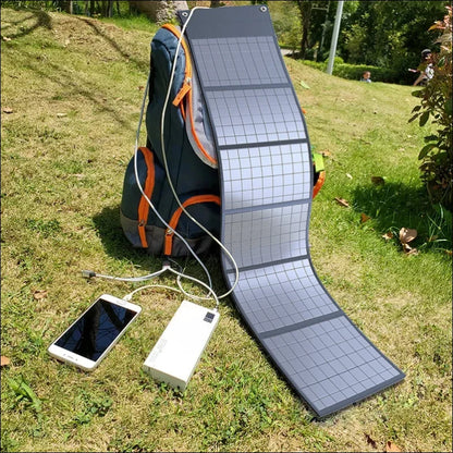 Tragbares solarpanel-ladegerät, angeschlossen an eine powerbank und ein smartphone auf einer wiese.