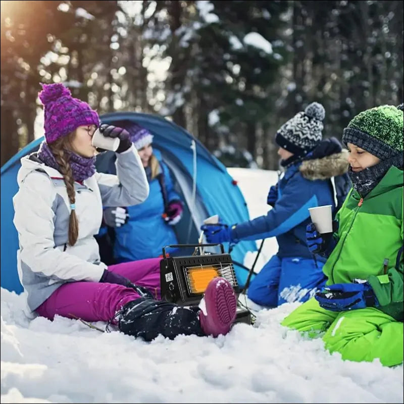 Eine gruppe von wintercampern sitzt im schnee und trinkt heiße getränke in der nähe eines blauen zeltes.