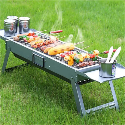 Klappbarer grill mit ausklappbaren stellflächen, beladen mit fleisch und gemüse für barbecue