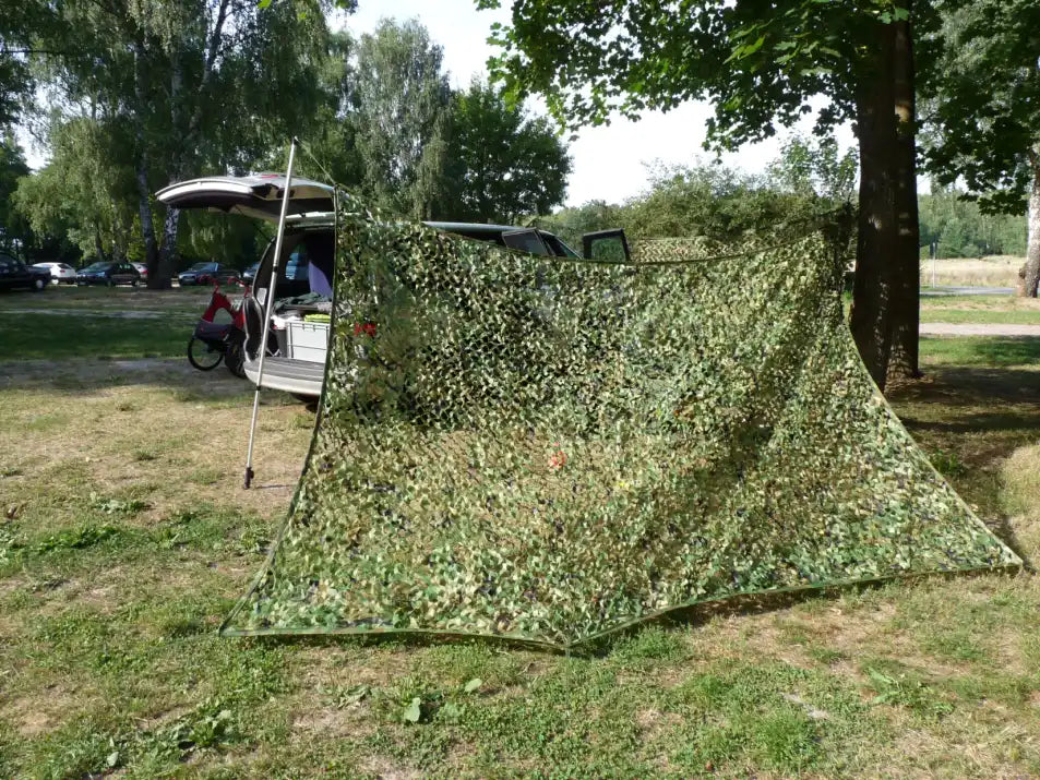 gruenes tarnnetz tarnt und verdeckt die sicht auf ein camper auto