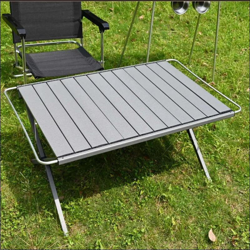 Tragbarer, klappbarer campingtisch mit aluminium-lattenrost und metallrahmen.