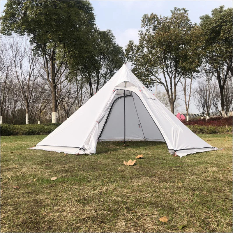 Nahaufnahme eines stabilen pyramidenzelts im feld mit bäumen - campingabenteuer deluxe